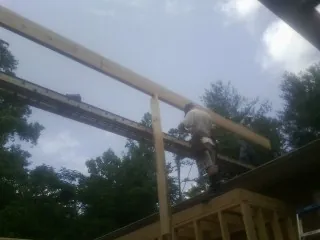Carpenter setting a ridge beam over a new addition frame — Ice Dam Removal by Roofing Brothers in Little Elm