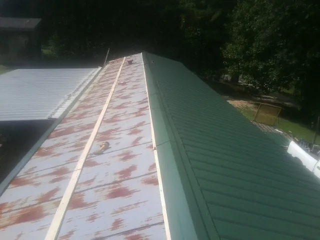Old rusted panels beside newly installed green metal roofing — Wind Damage Roof Repair by Roofing Brothers in Little Elm