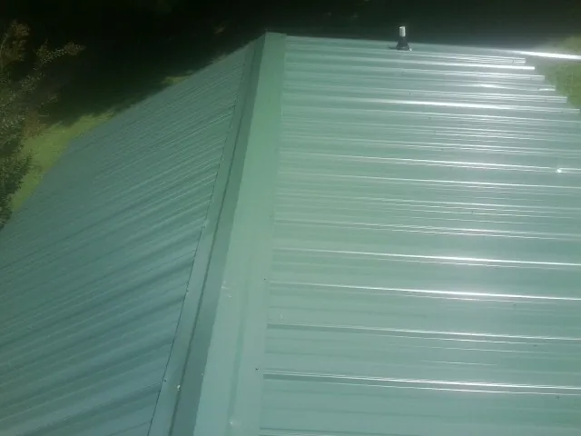 New green metal panels meeting at the ridge of a roof — Flat Roof Repair work by our crew in Little Elm