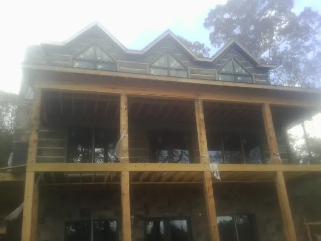 Dormers and porch framing on a large log home under construction — Roof Coating work by our crew in Little Elm