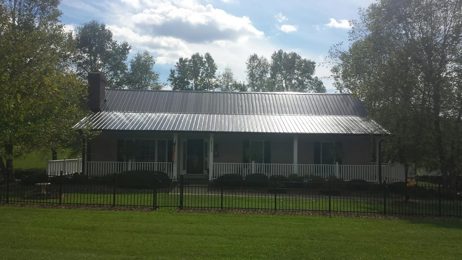 Gray metal roof on a brick ranch with a full width front porch — Gutter Guard Installation work by our crew in Little Elm