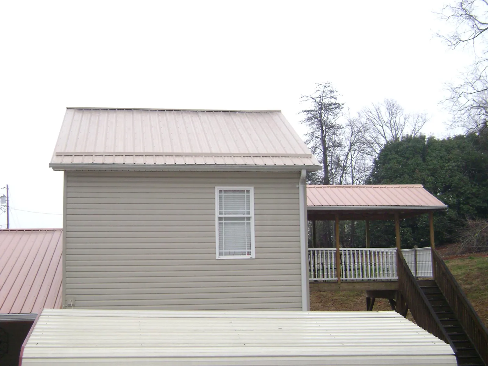 Tan metal roofs on a two story addition and attached porch, from a Roof Replacement job in Little Elm
