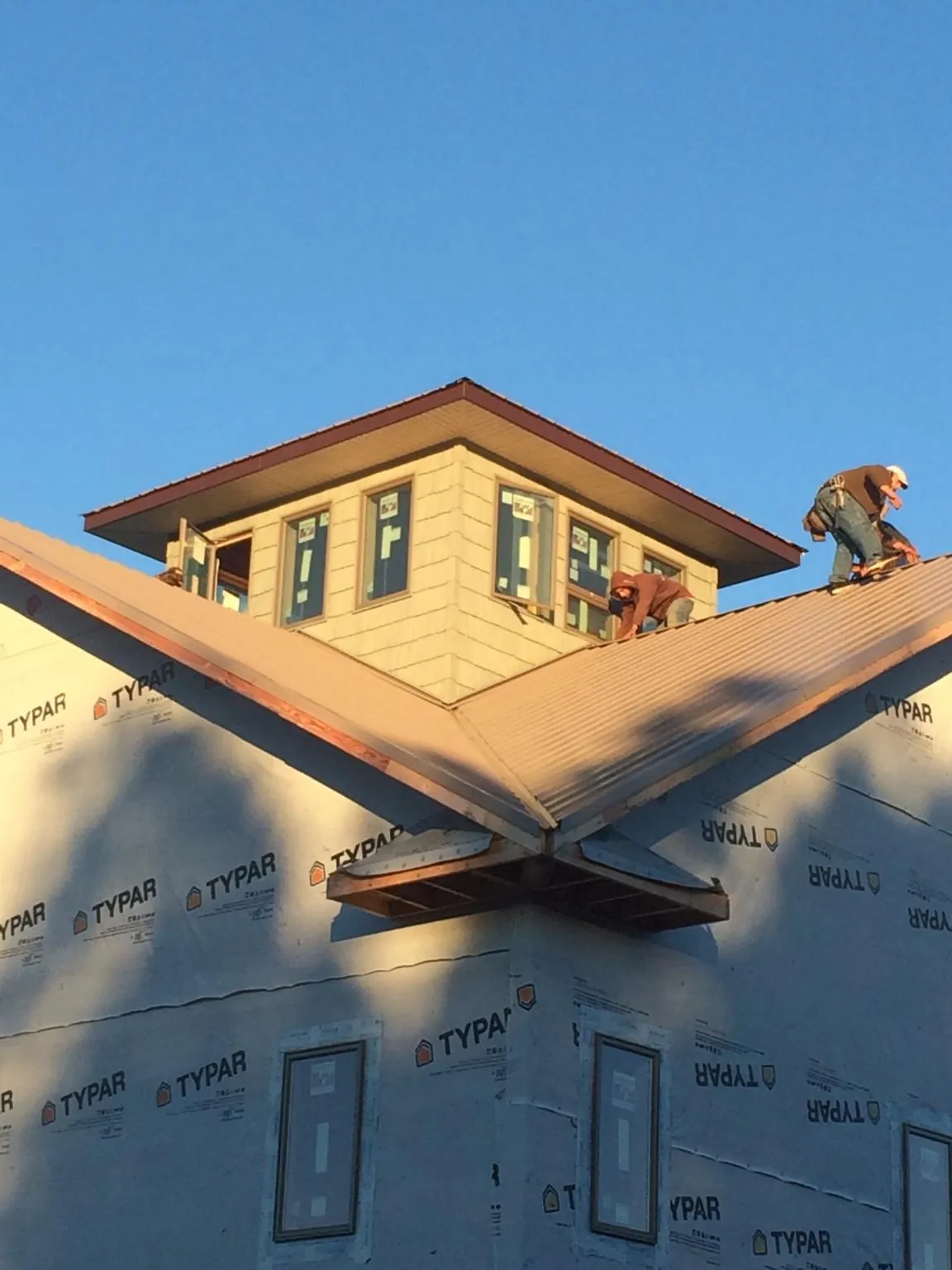 Roofers working around a rooftop cupola on a new metal roof at sunset — Roof Waterproofing in Little Elm by Roofing Brothers